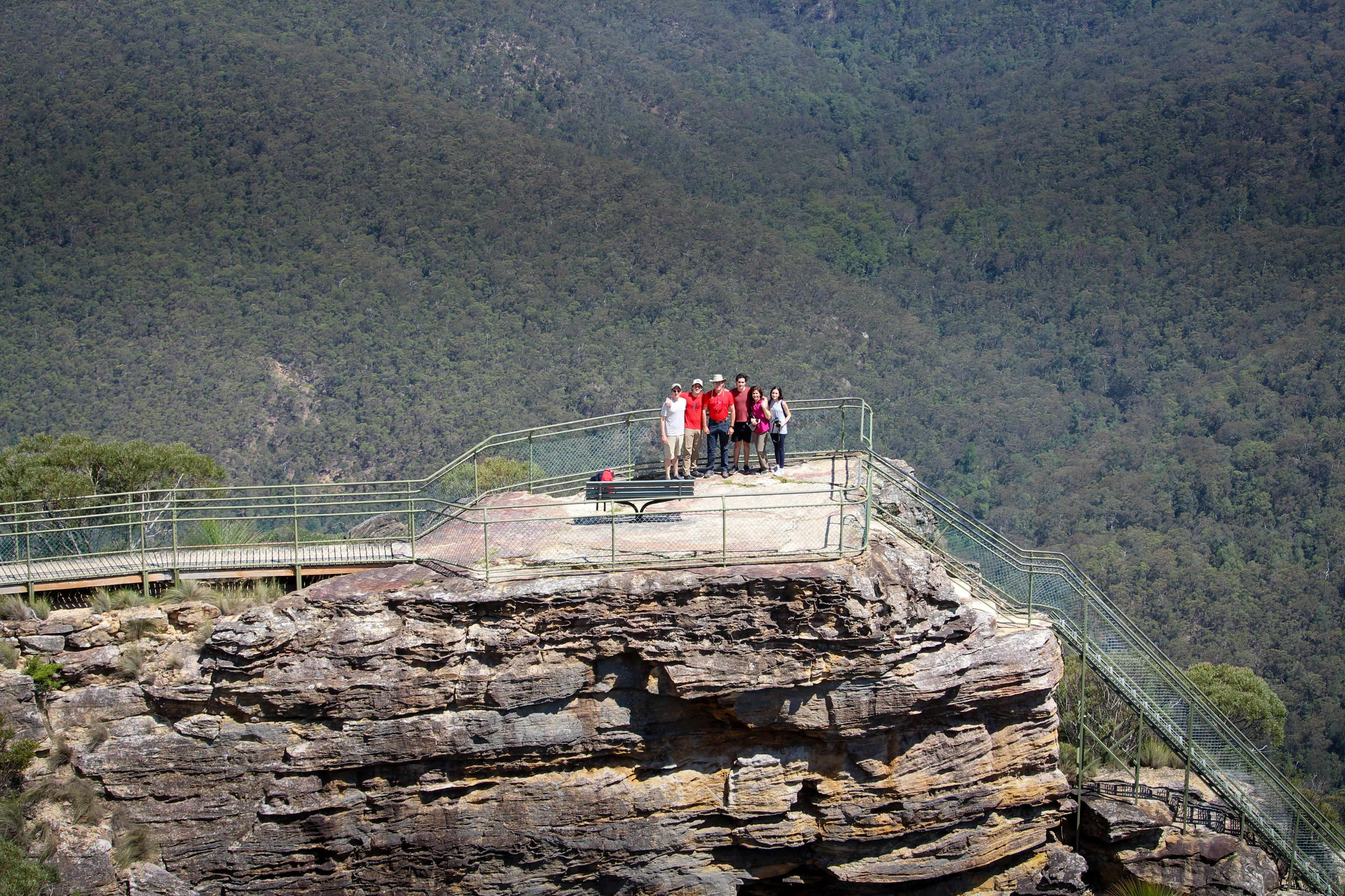 A group of walkers at a rocky outcrop overlooking the vast Grose Valley
