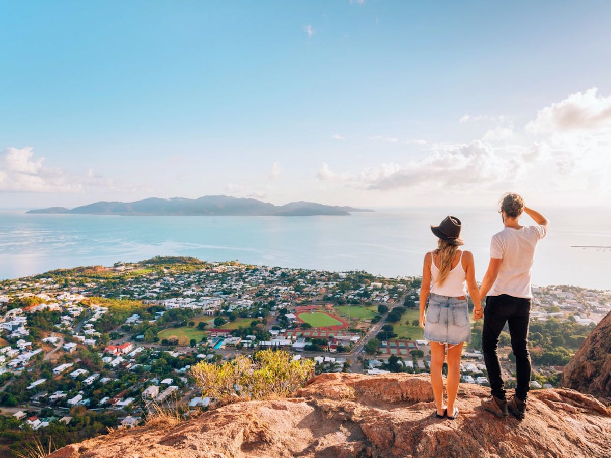 Two people on a hill looking out over a body of water Two people on a hill looking out over a body of water