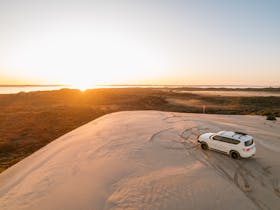 Tour vehicle parked on large dune over looking Lake George on sunrise