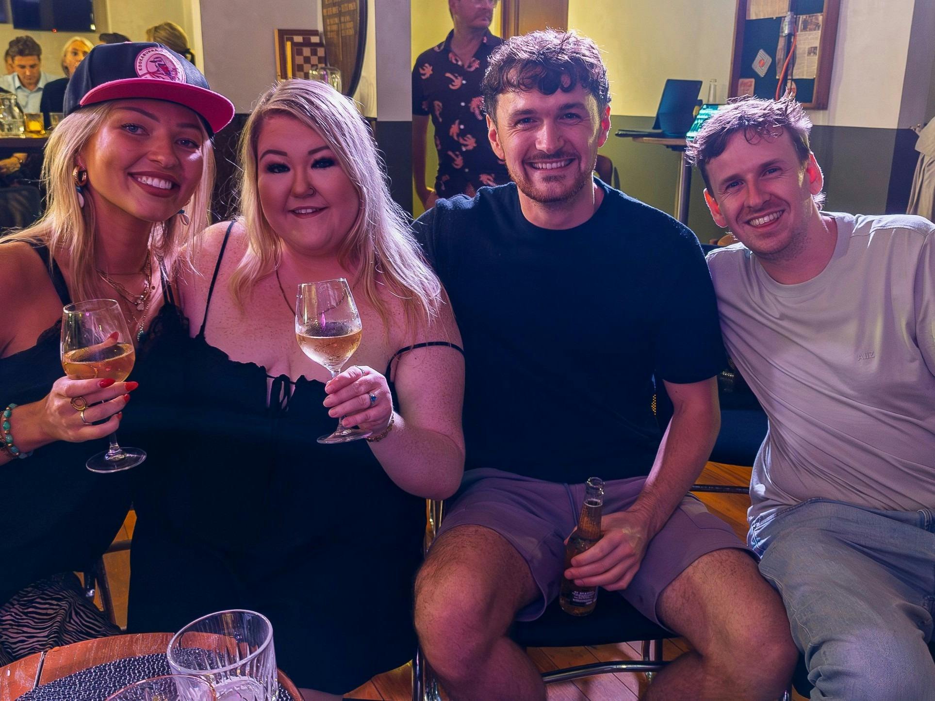 Friends enjoying drinks and laughs at a comedy night at The Nelson Hotel
