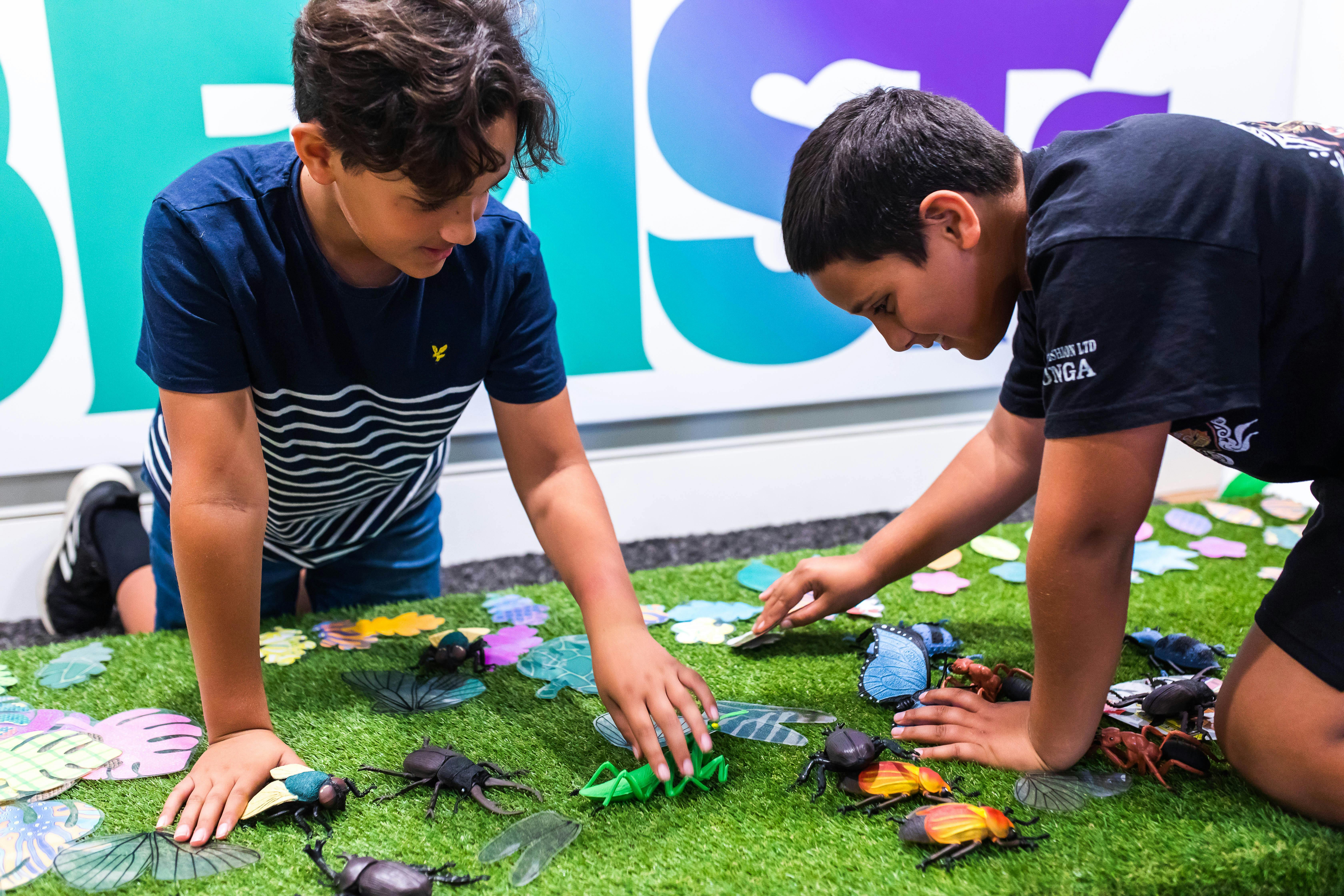 Two young boys playing with plastic insects at 'Minibeasts' Imaginarium exhibition