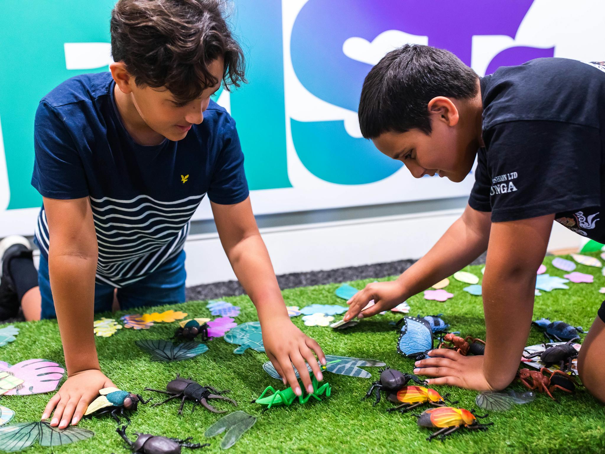 Two young boys playing with plastic insects at 'Minibeasts' Imaginarium exhibition
