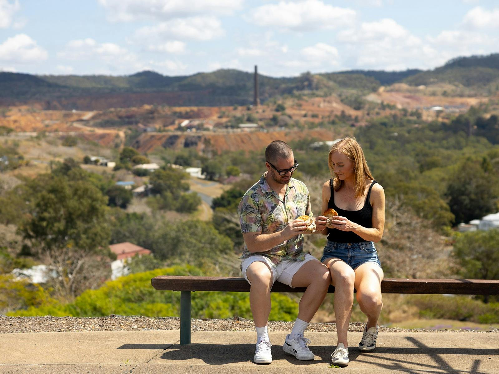 Young man and woman enjoying a meat pie at a lookout at Mount Morgan Young man and woman enjoying a meat pie at a lookout at Mount Morgan