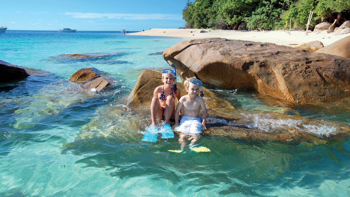 Children in snorkelling gear on boulder at beach at Fitzroy Island