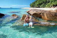 Children in snorkelling gear on boulder at beach at Fitzroy Island