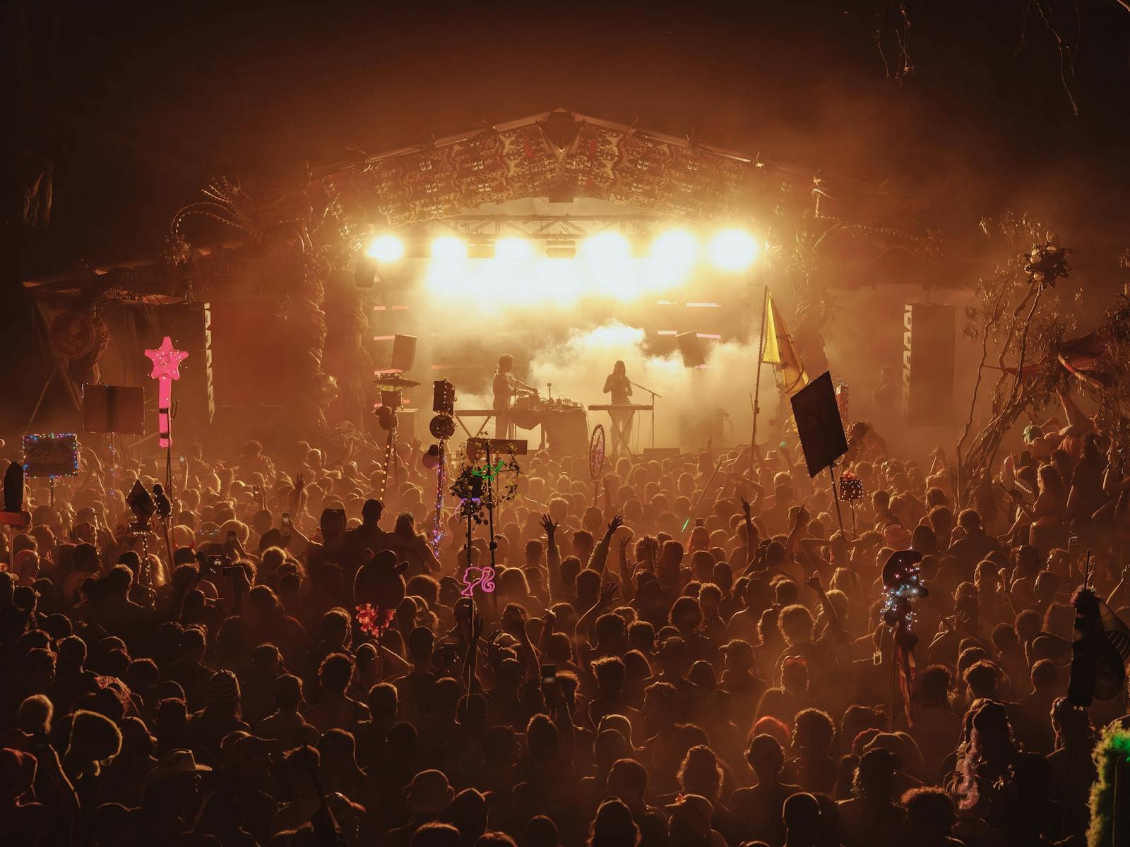 People celebratiing whilst watching live music at night on the Grove Stage at Strawberry Fields Fest