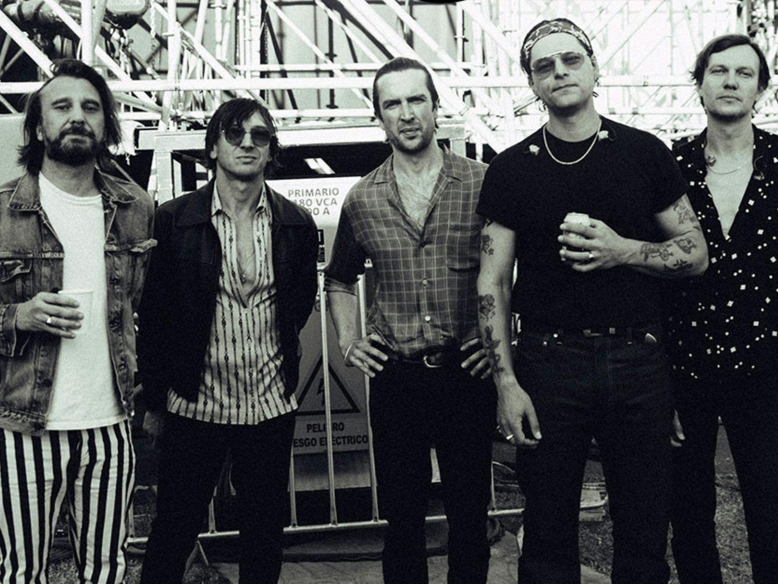 The band membrs from jet standing in a line looking directly at the camera