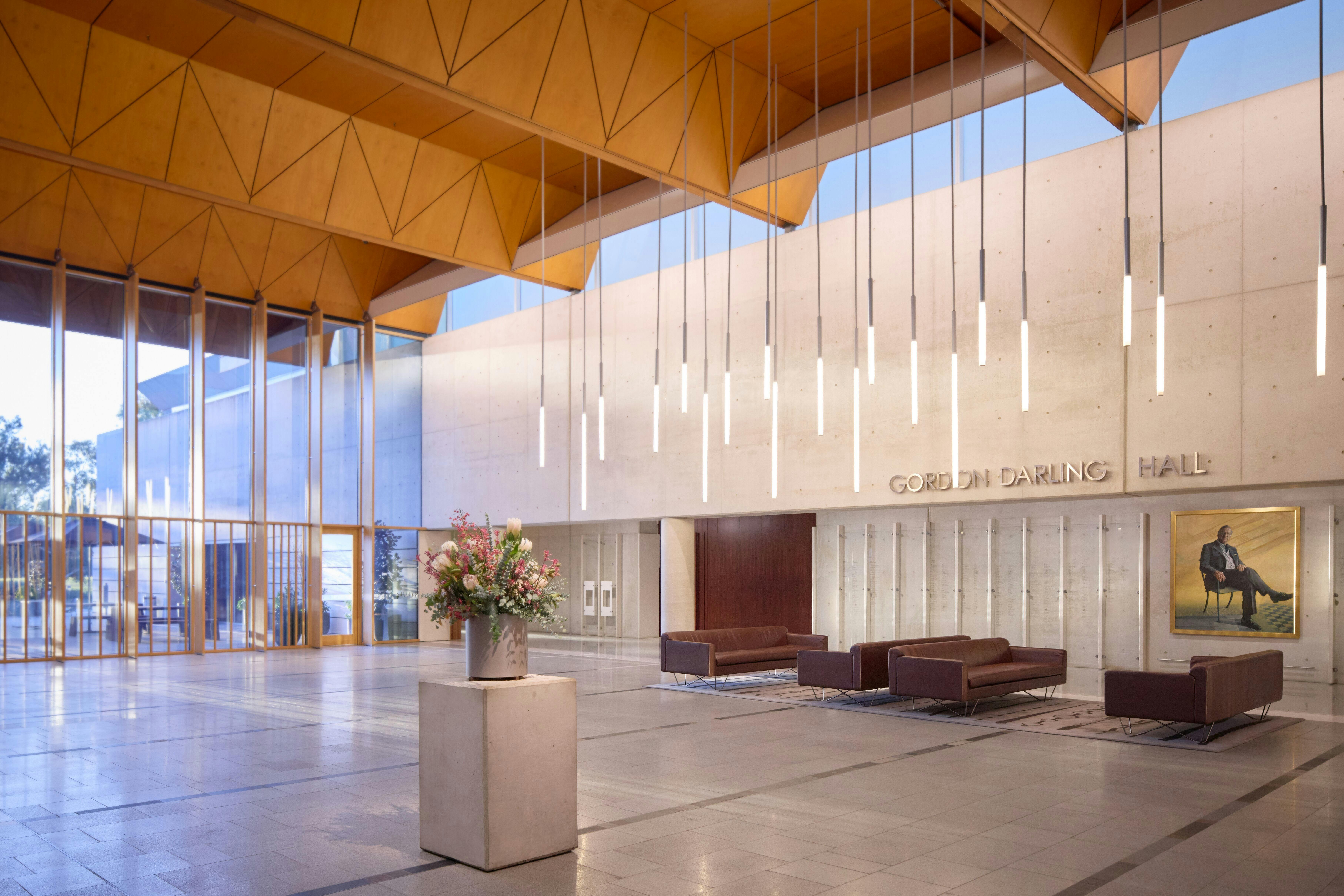 A shot of the brightly lit Gordon Darling Hall, including botanical arrangements and sleek seating.