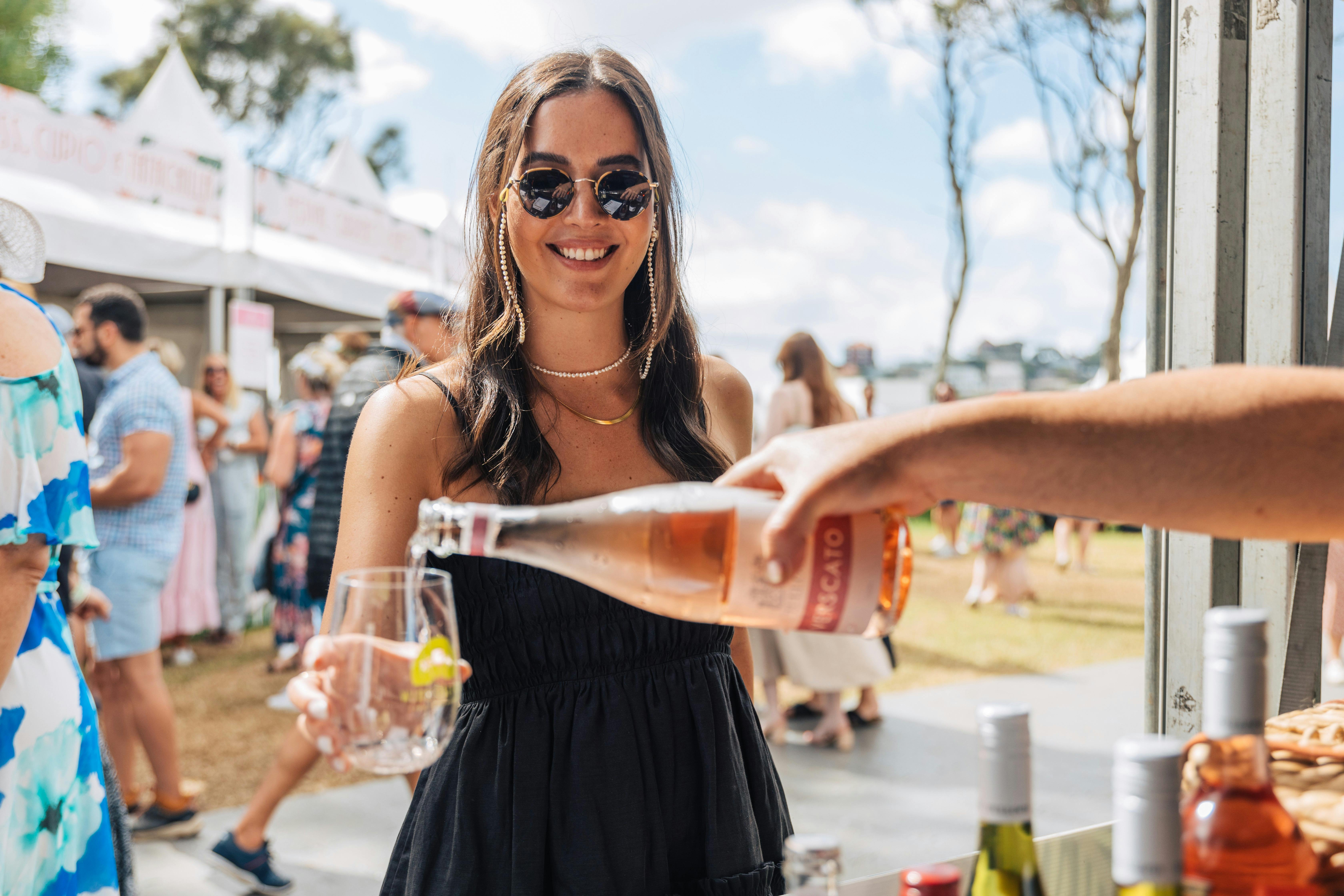 Woman holding her wine glass with wine being poured in from wine bottle