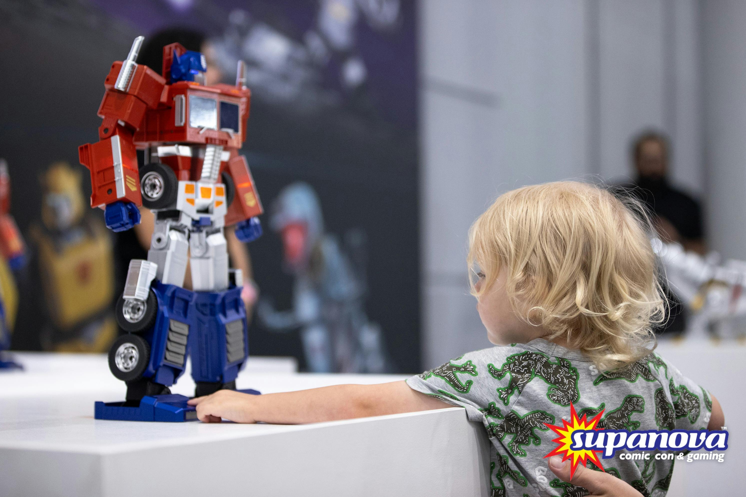 A young child gazes up at an Optimus Prime figure on display at Supanova Comic Con & Gaming