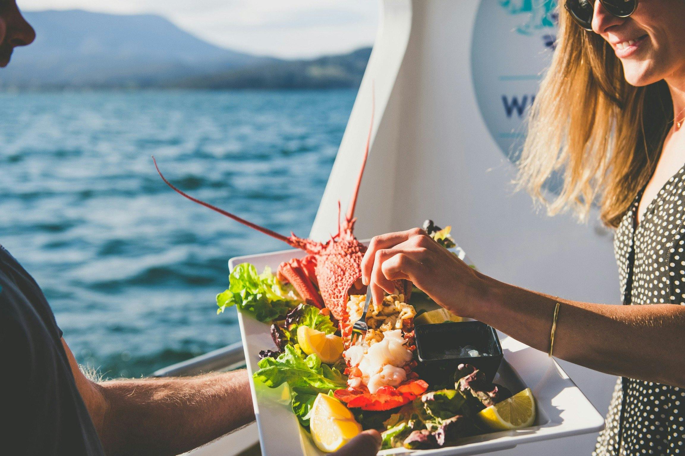 A guest samples cooked Tasmanian rock lobster on the Deep-to-Dish: Tasmanian Seafood Experience