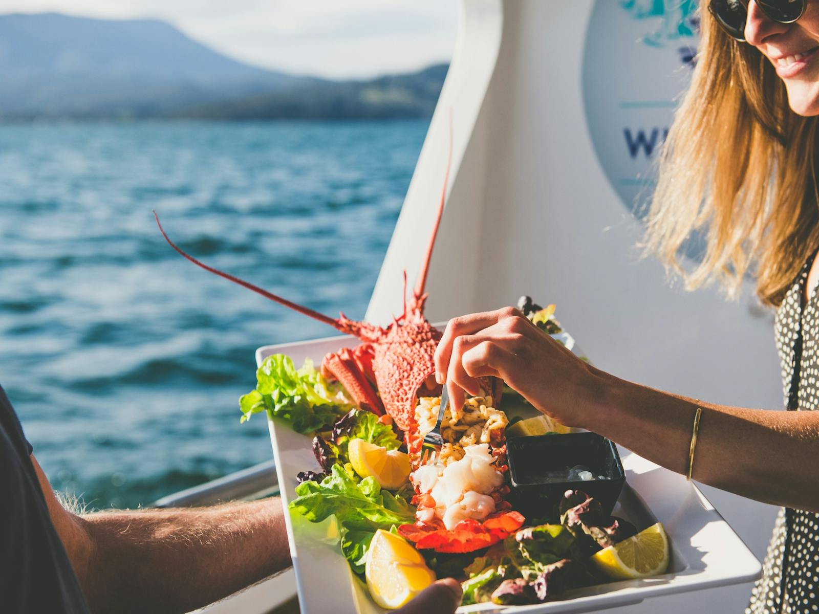 A guest samples cooked Tasmanian rock lobster on the Deep-to-Dish: Tasmanian Seafood Experience