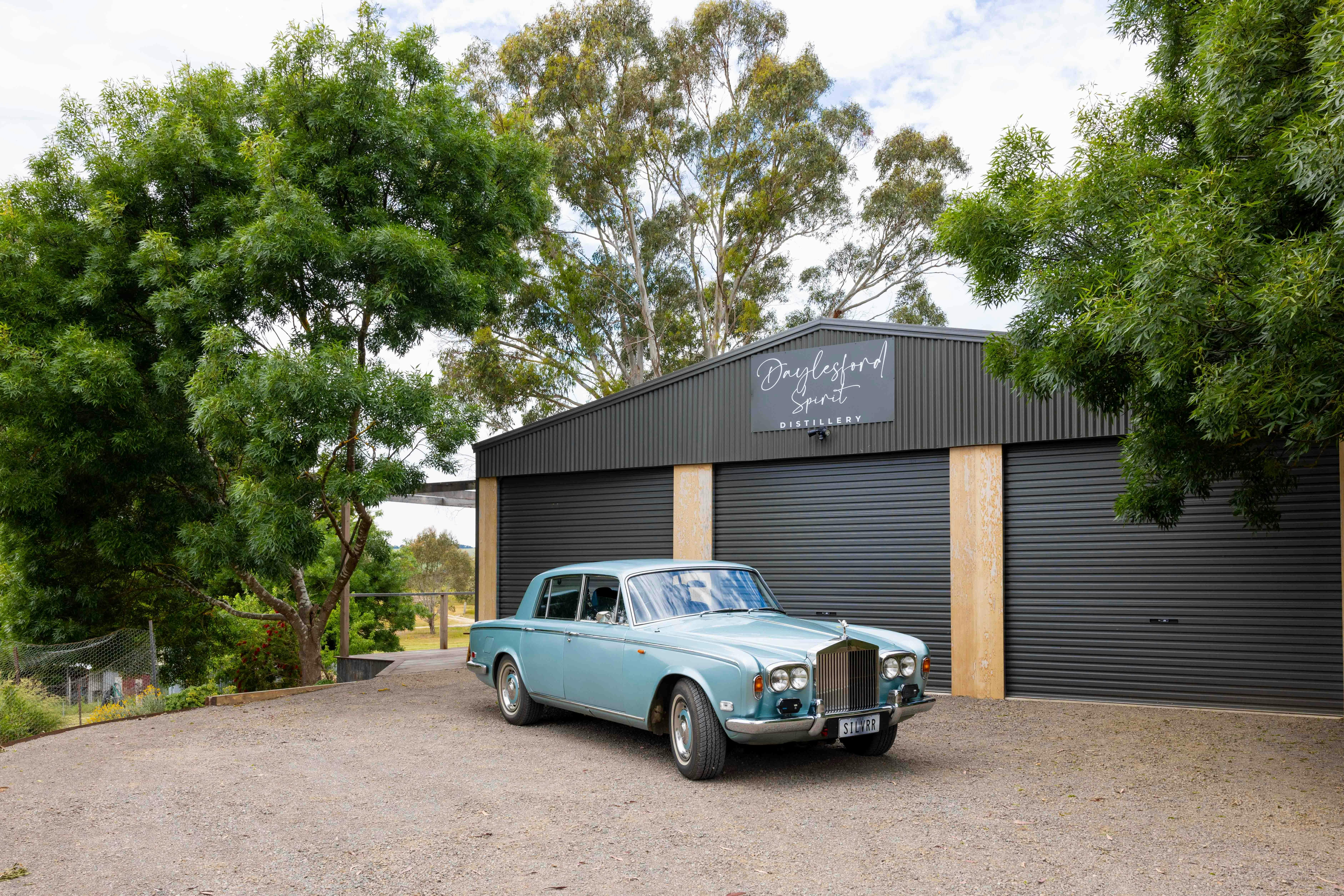 Silver-blue coloured vintage Rolls Royce parked outside the working gin distillery.  Daylesford.