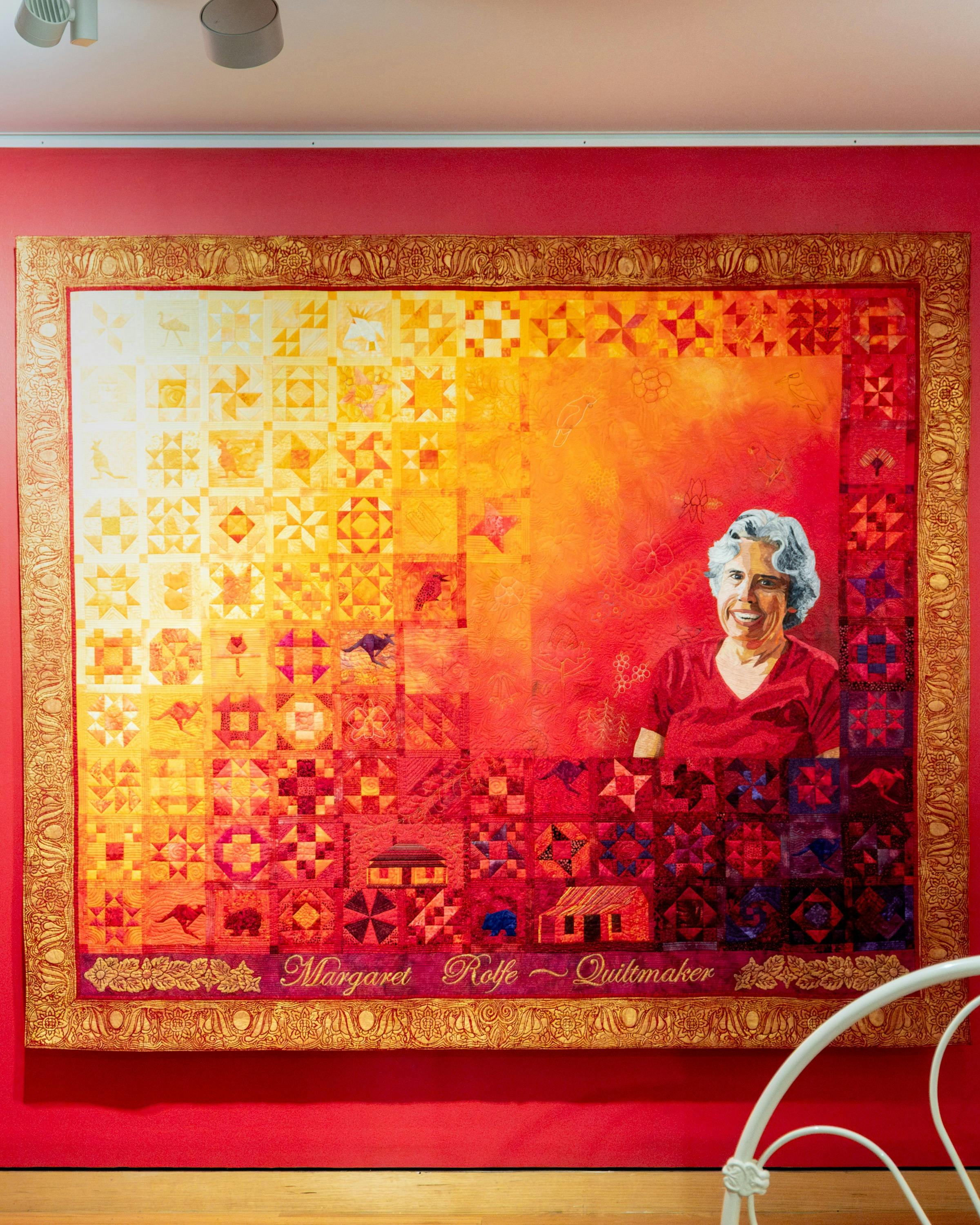 The Quiltmaker quilt by Jenny Bowker depicting Margaret Rolfe in bright yellows, oranges and reds