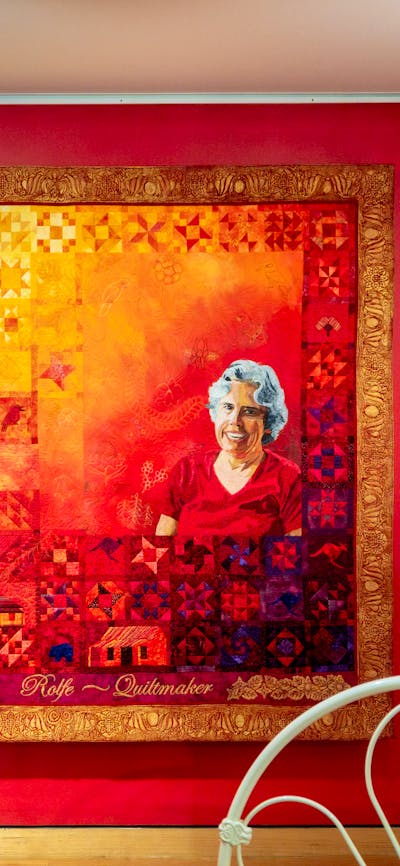 The Quiltmaker quilt by Jenny Bowker depicting Margaret Rolfe in bright yellows, oranges and reds