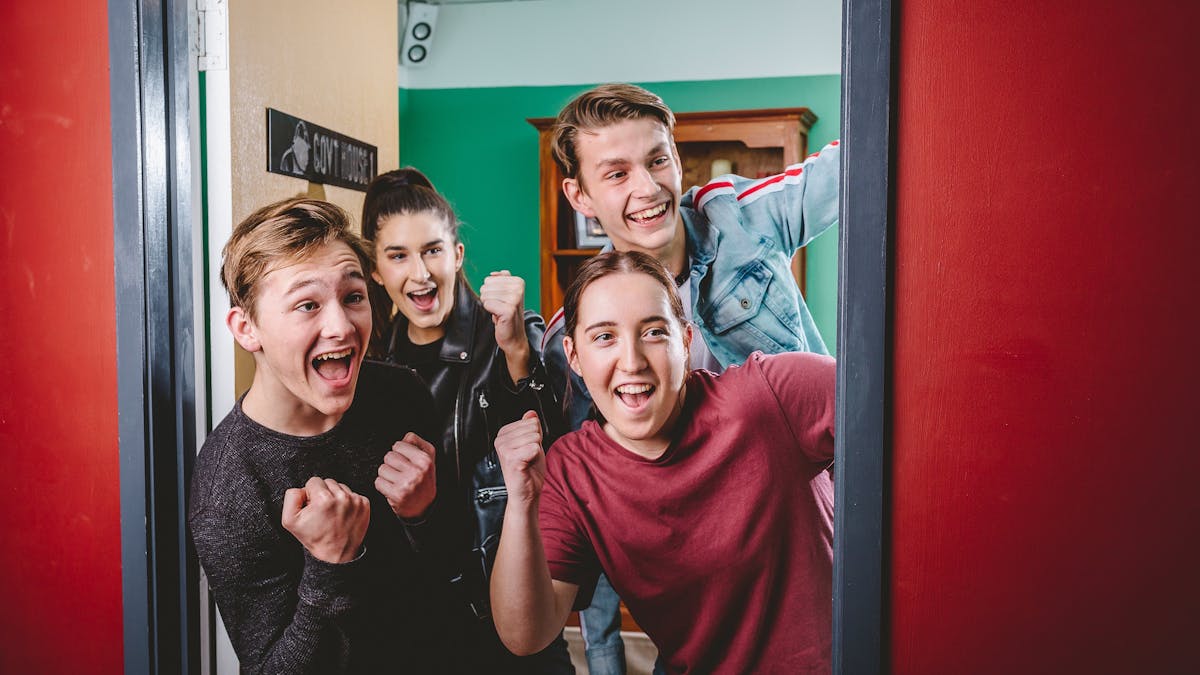 Group of 4 cheering as they break out of the escape room