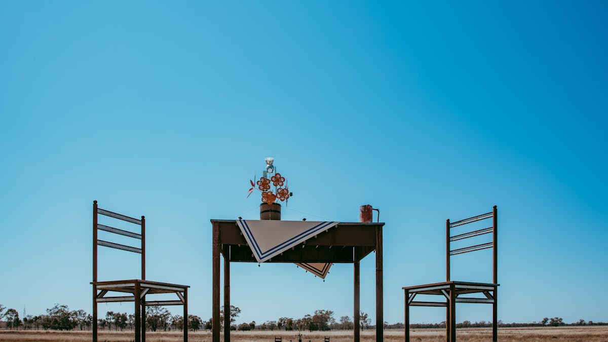 A supersized table and chairs sculpture in an open paddock A supersized table and chairs sculpture in an open paddock