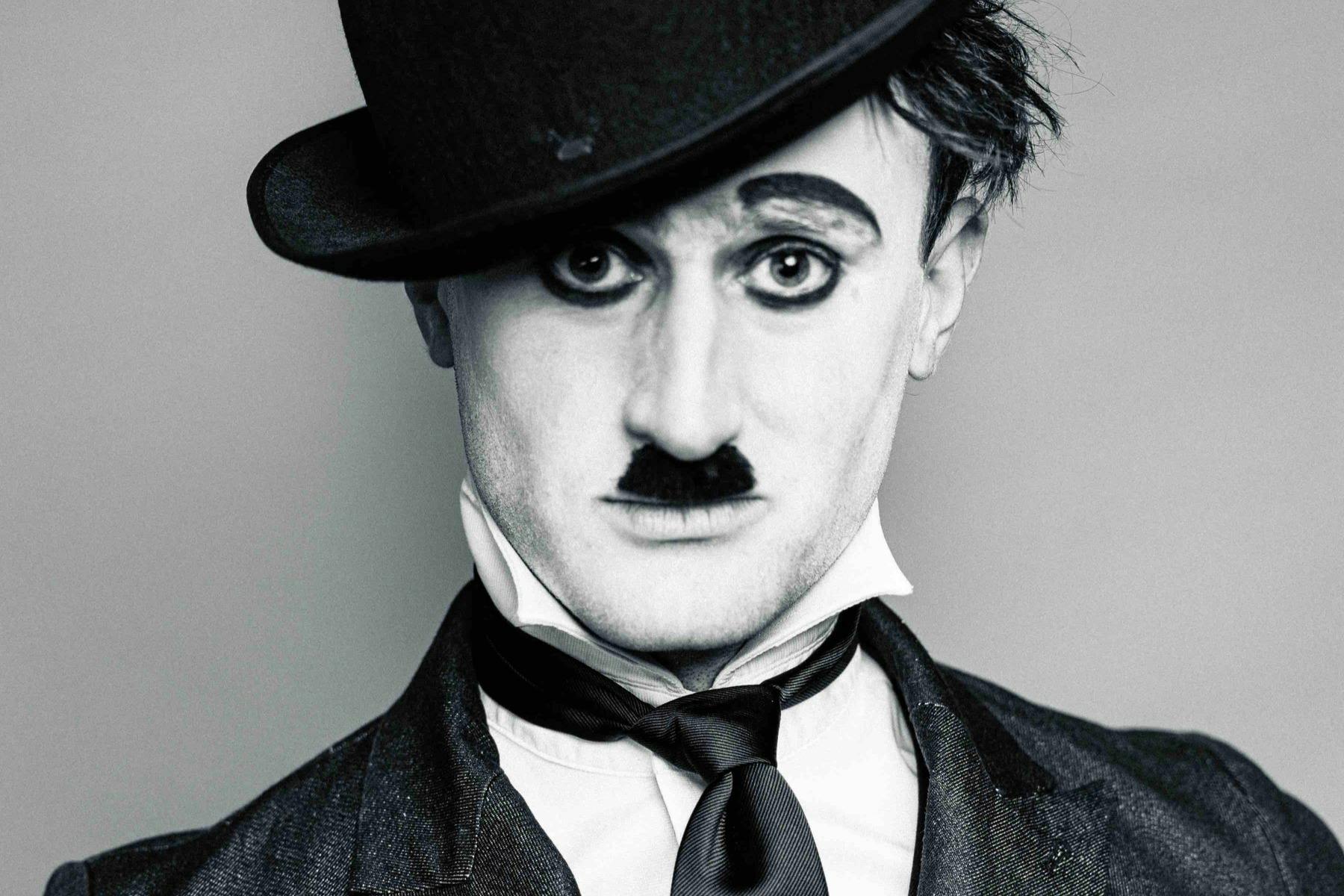 A black and white close up of a young man dressed as Charlie Chaplin