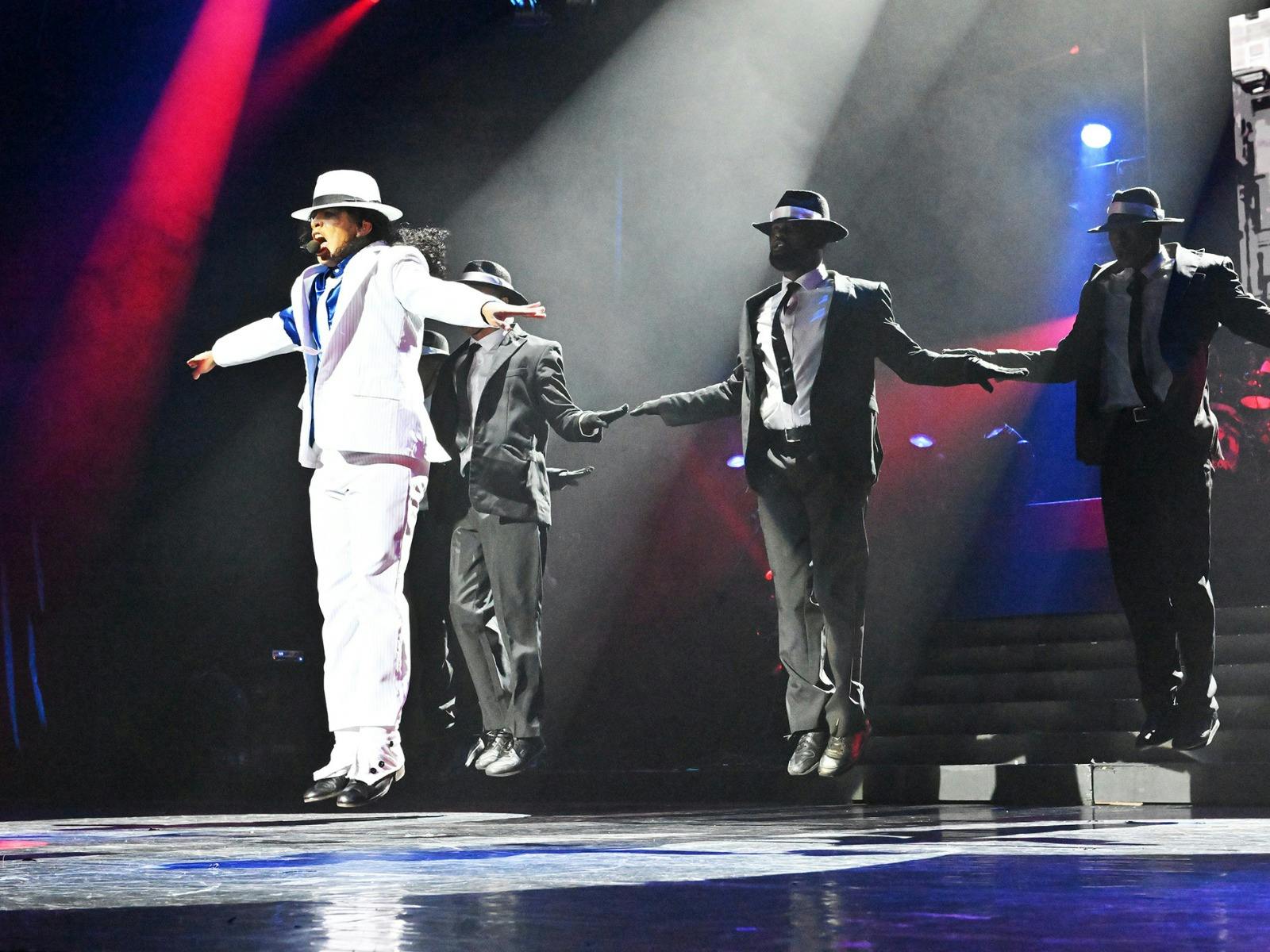 Michael Jackson tribute artist on stage performing in front of three backup dancers