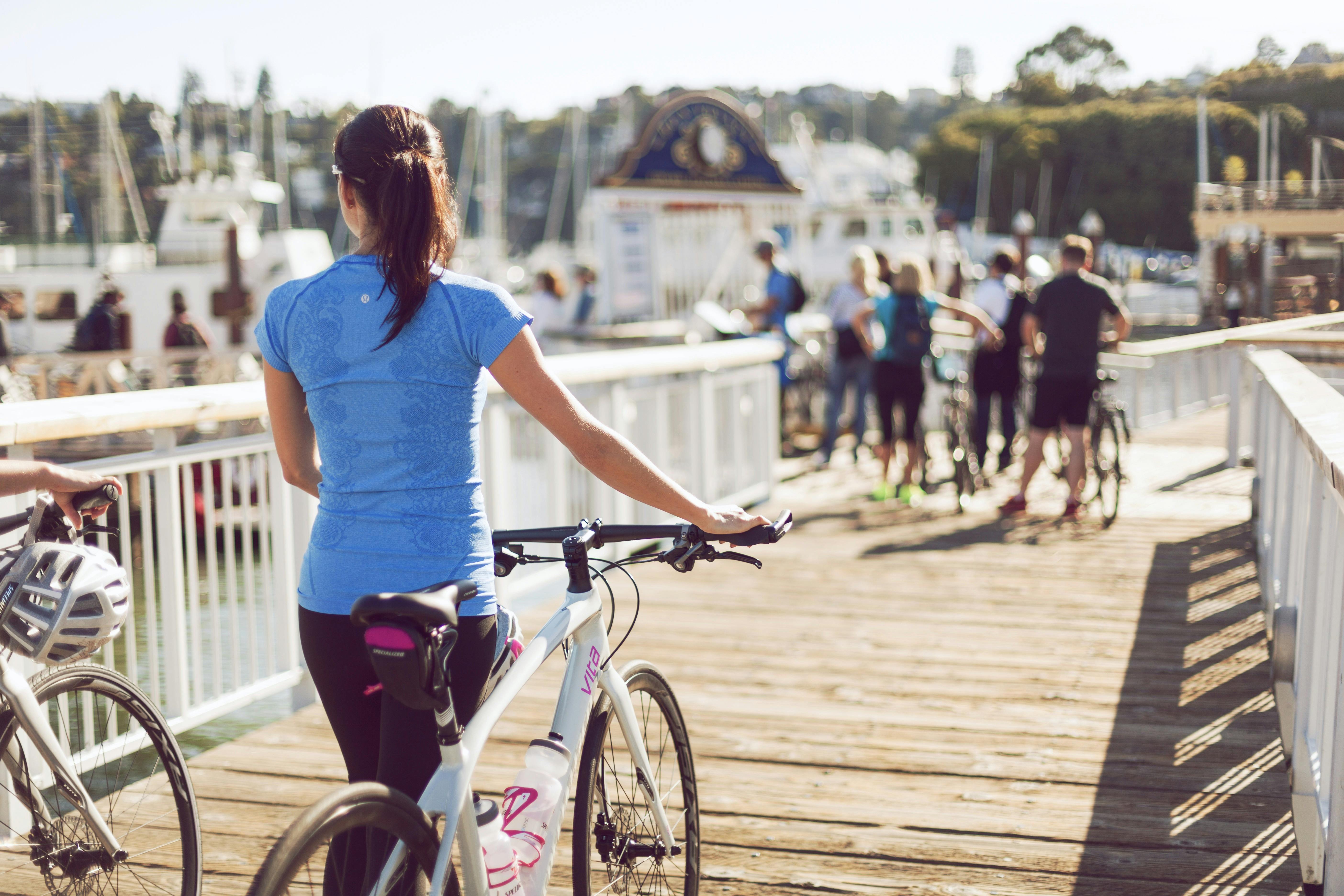 lady wheeling bike on bridge