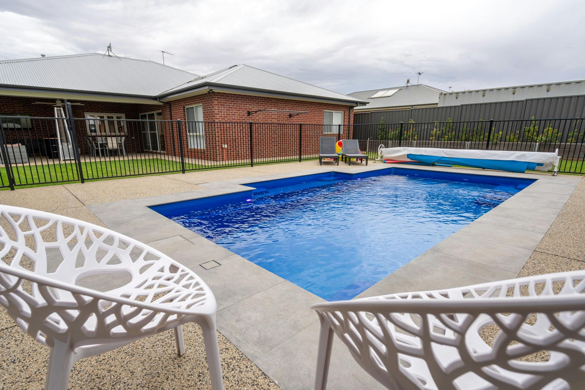 뒷마당에는 흰색 카리스 2개 일광욕용 라운지 2개 수영장 장난감이 있는 수영장 공간이 있습니다. 수영장은 가열되어 있습니다