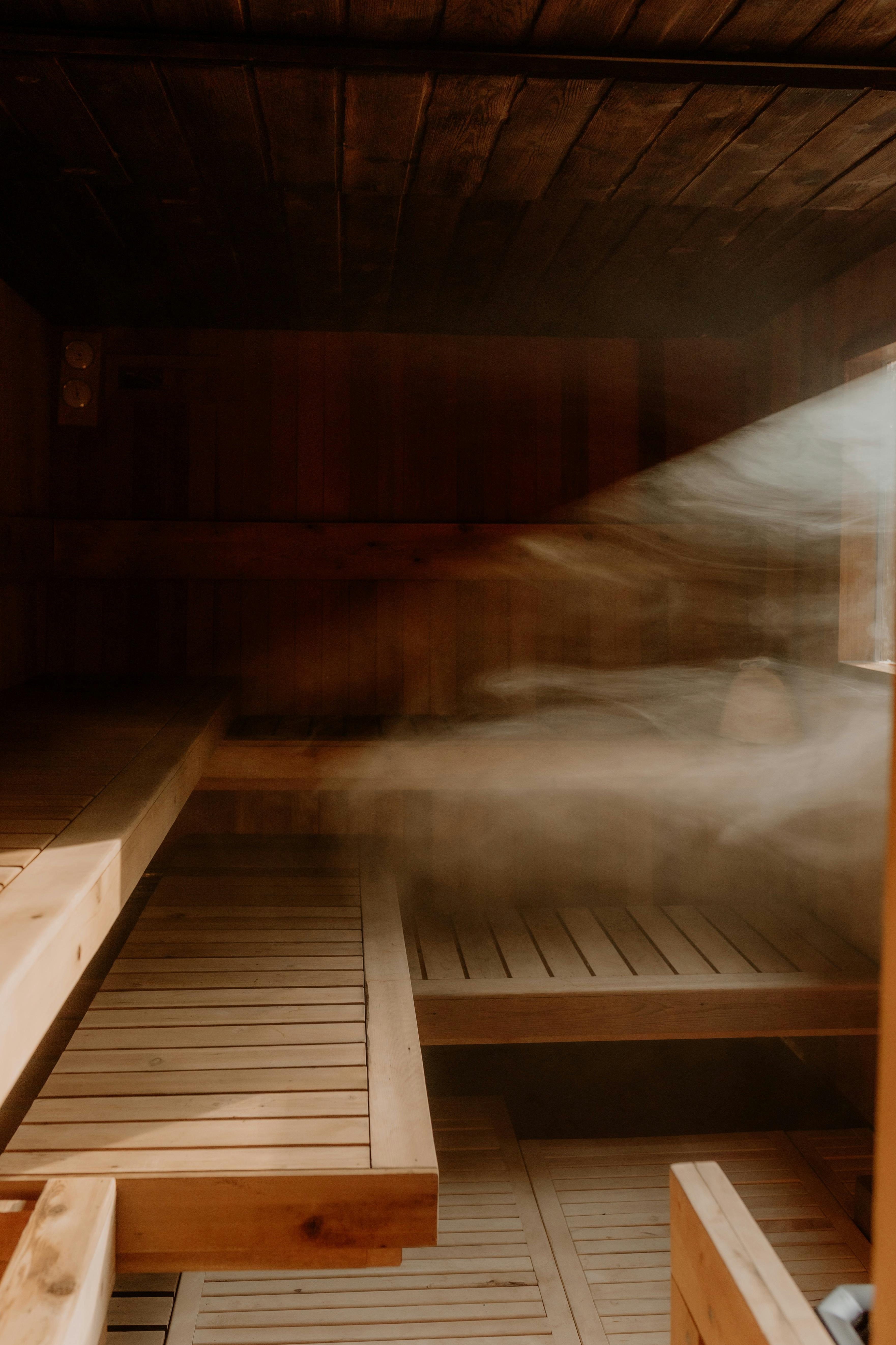 Steam drifting through a timber-lined sauna illuminated by natural light.