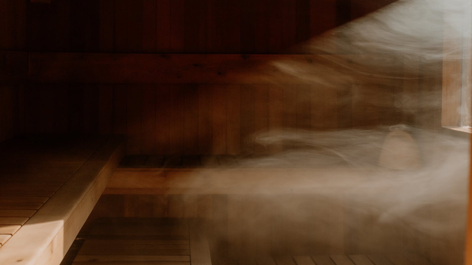 Steam rises through the sauna as heat and light fill the timber interior.