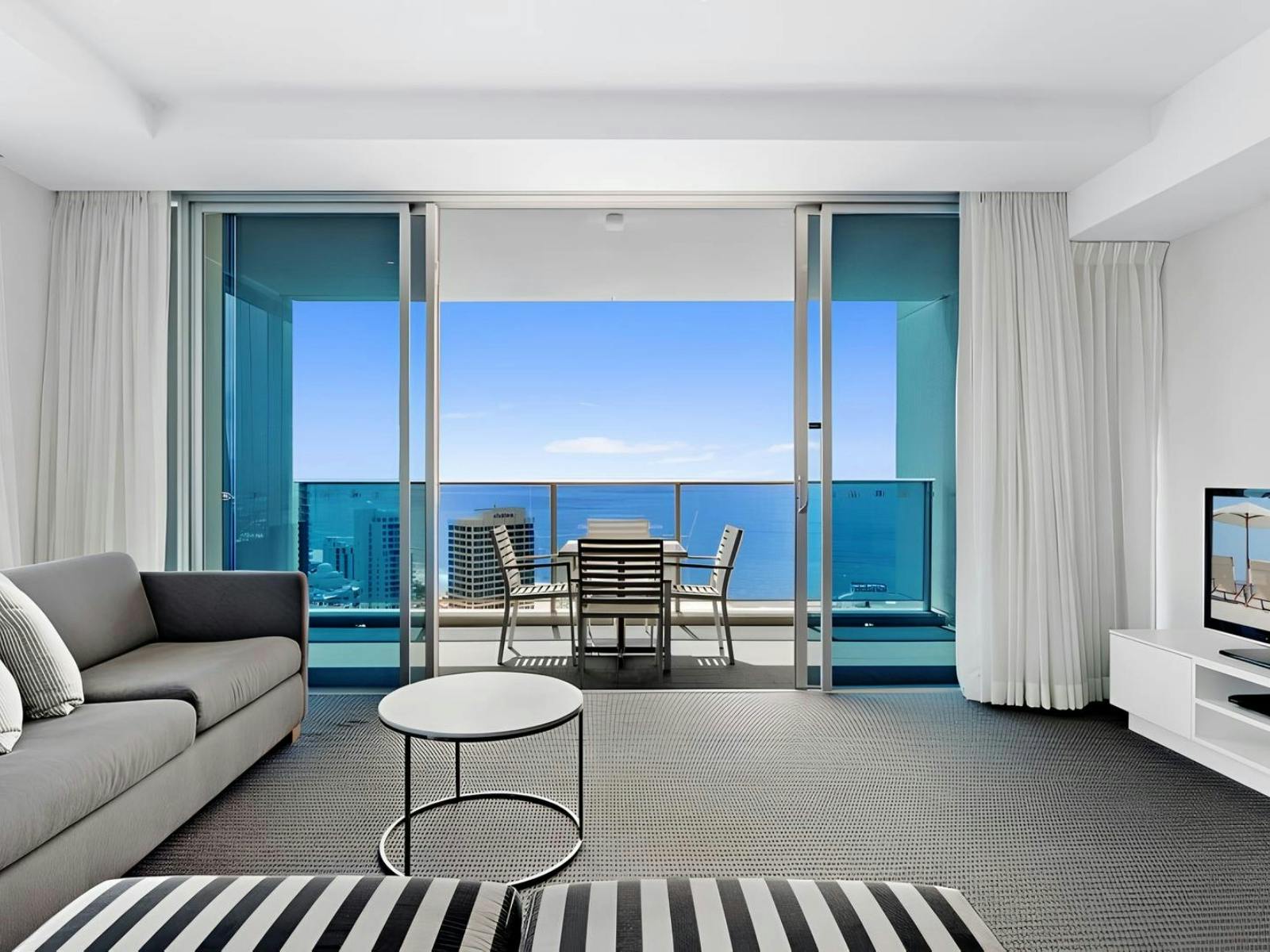 Lounge room with TV, over looking balcony with ocean views Hilton Residences Surfers Paradise Lounge room with TV, over looking balcony with ocean views Hilton Residences Surfers Paradise