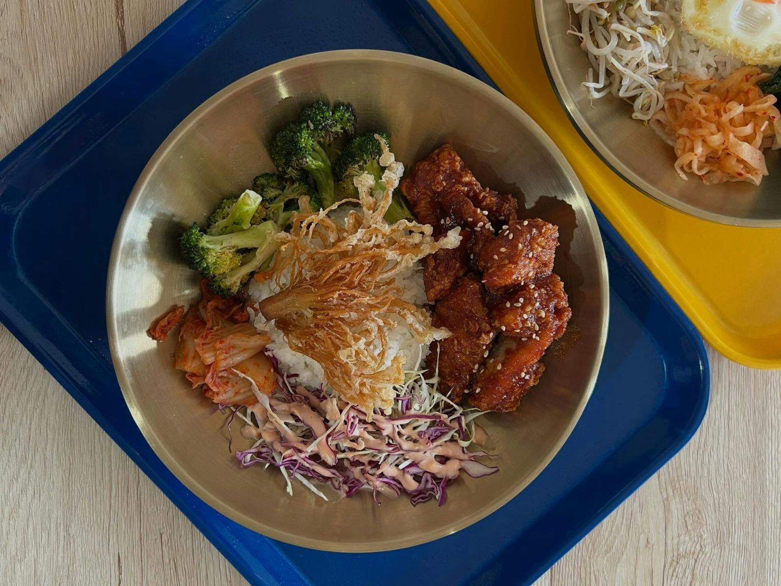 Korean fried chicken bowl with rice, kimchi, vegetables and sesame-glazed chicken.