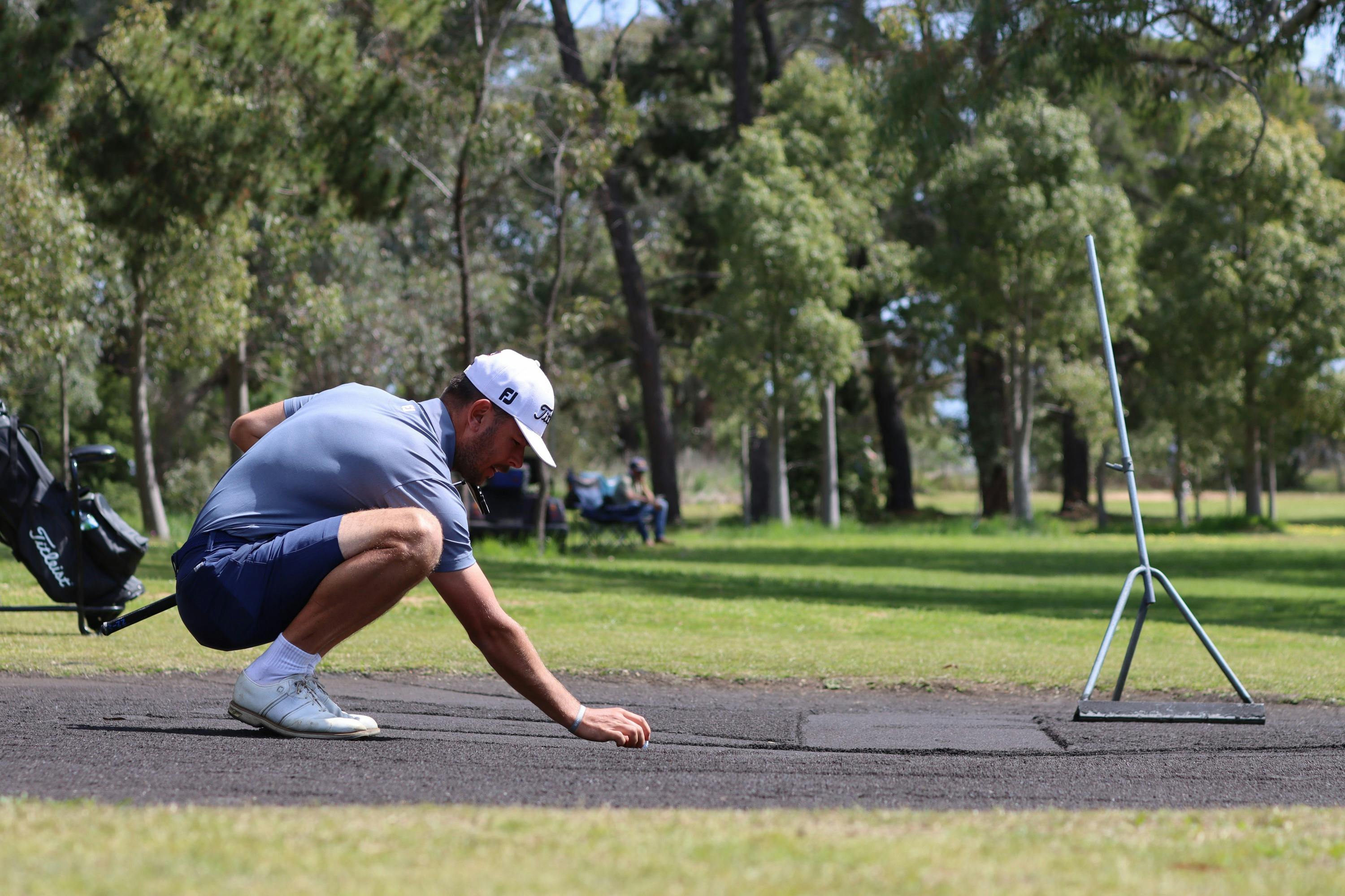 Male golfing lining up a putt on sand greens
