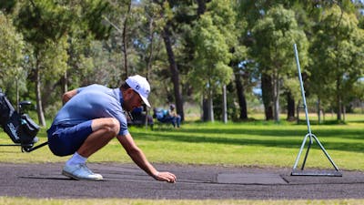 Male golfing lining up a putt on sand greens