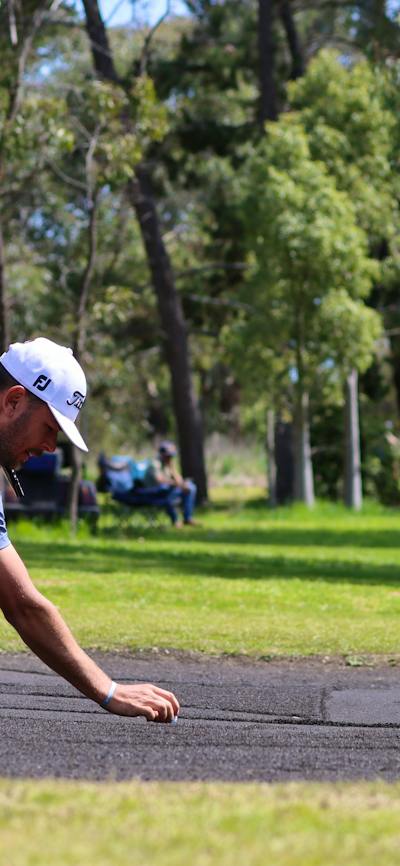 Male golfing lining up a putt on sand greens