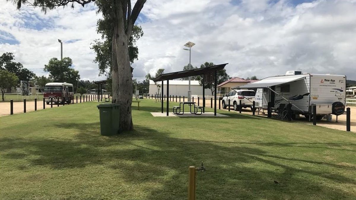 Shaded picnic bench  near grassed area and tree and caravan with 4WD parked in the RV Park