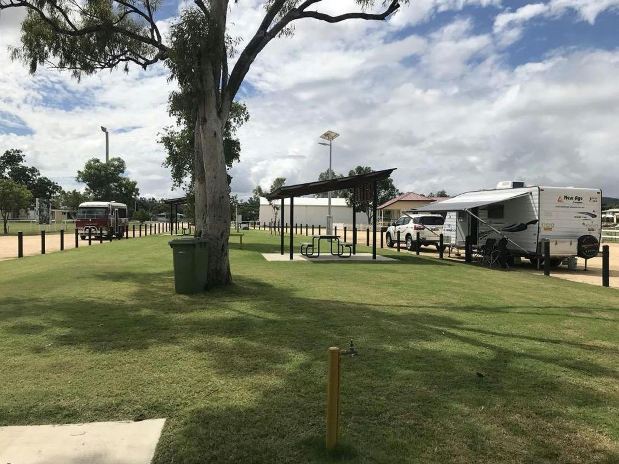 Shaded picnic bench near grassed area and tree and caravan with 4WD parked in the RV Park Shaded picnic bench near grassed area and tree and caravan with 4WD parked in the RV Park