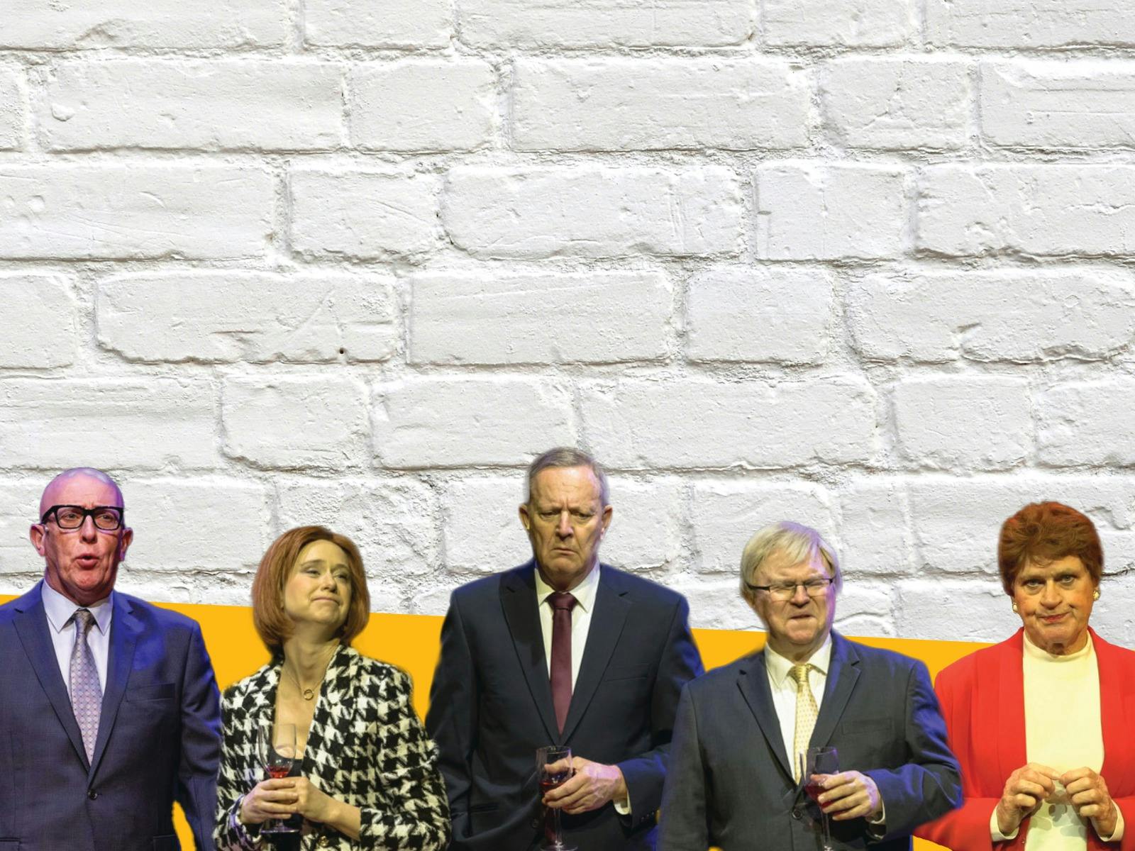 A group of five people standing in front of a white brick wall.