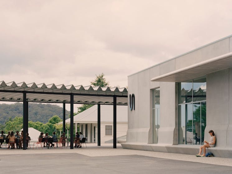 A photo of the concrete facade of the Art Museum and visitors enjoying their meals at Ramox Cafe