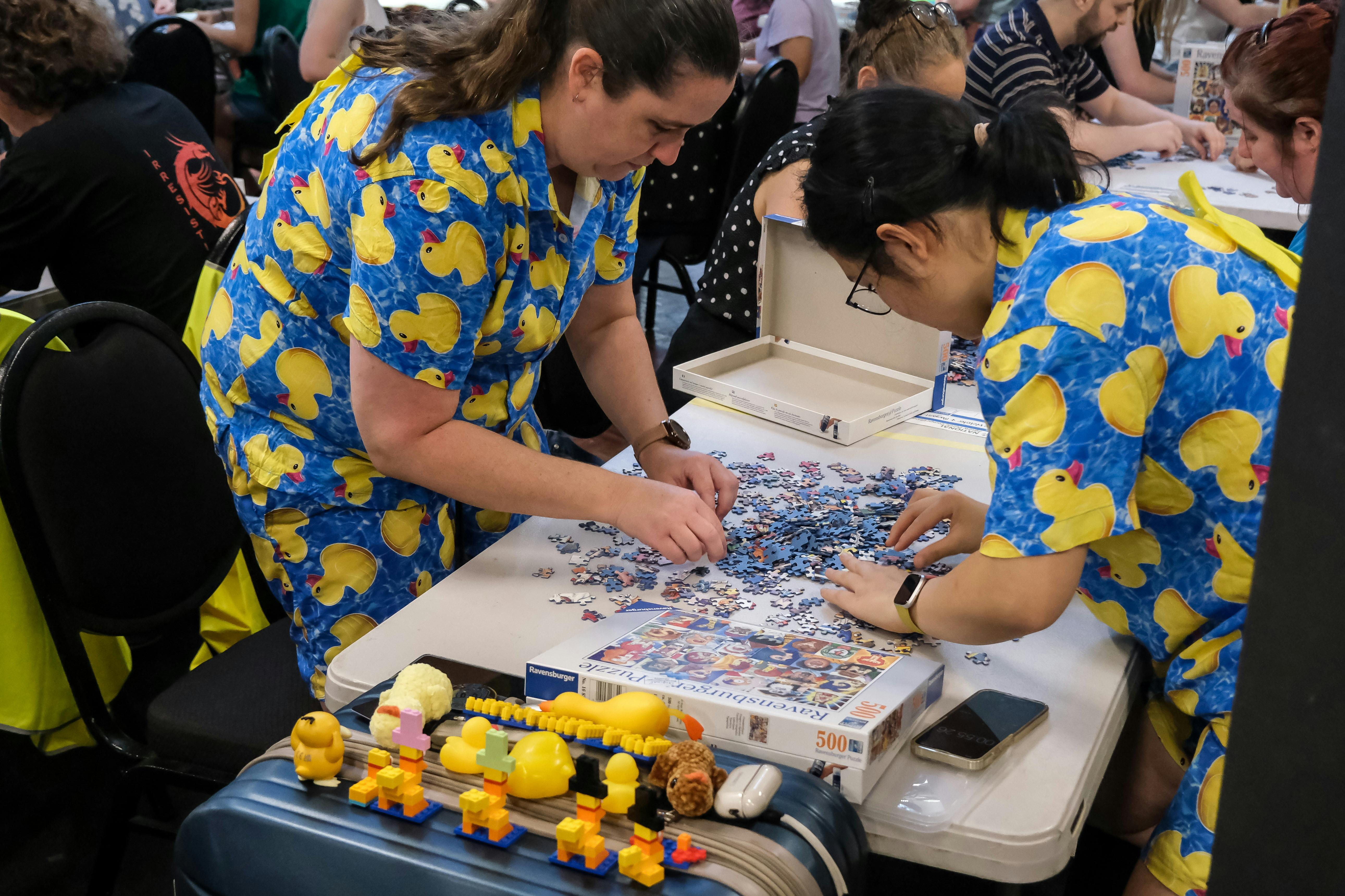 Two women in duck outfits complete a puzzle