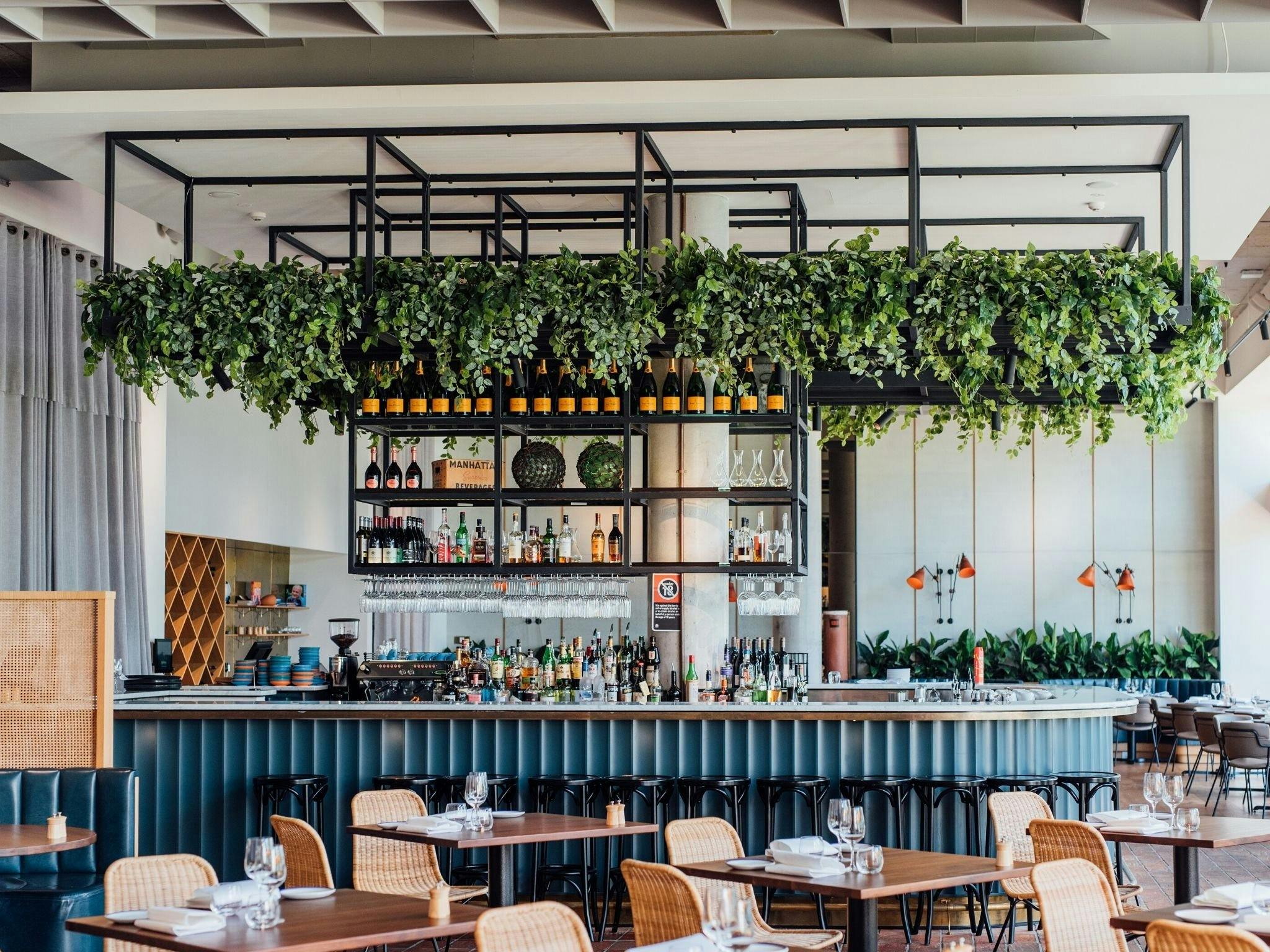 interior shot of Rick Stein at Bannisters shows navy blue bar with folliage hanging from shelving ab