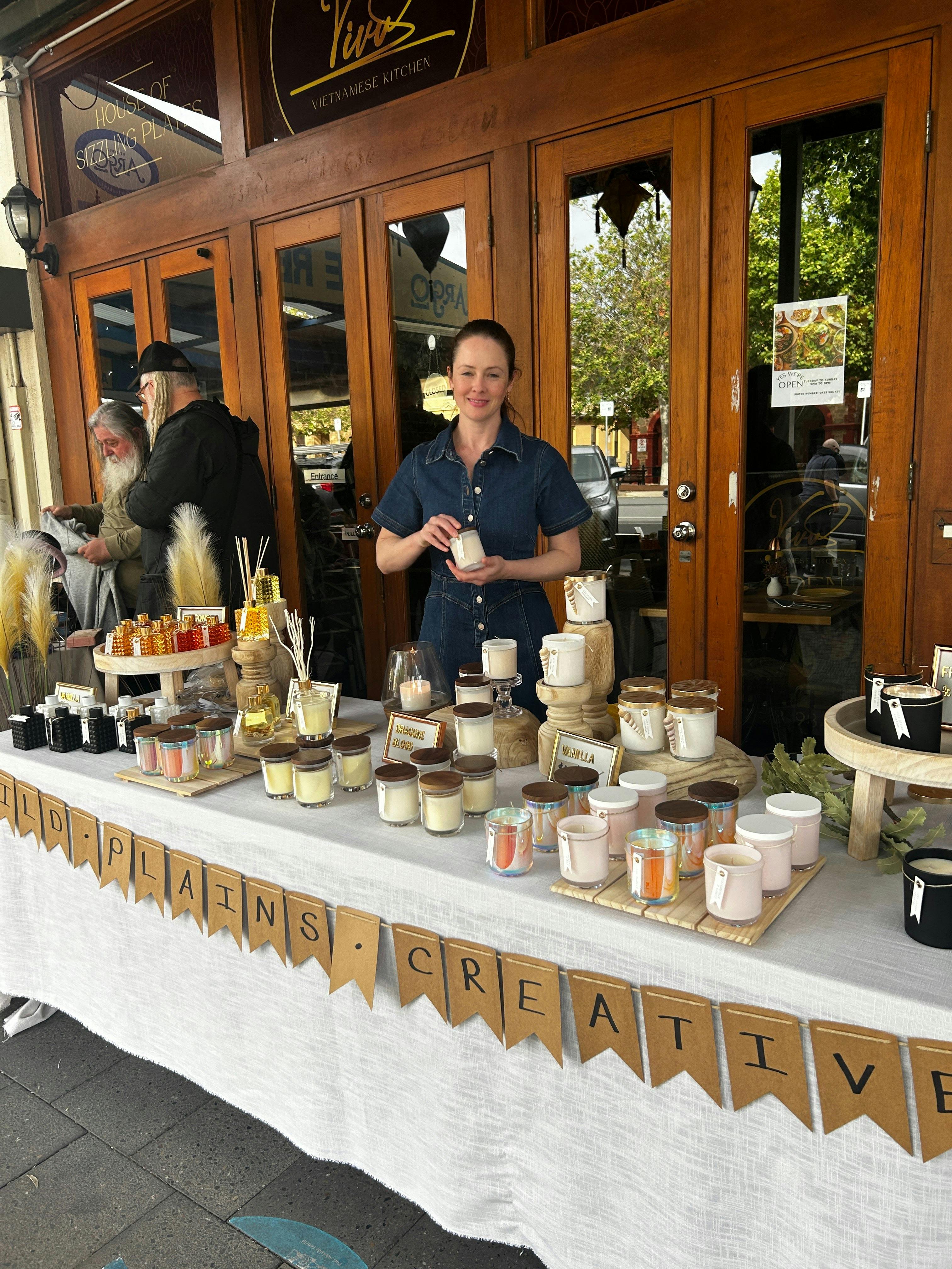 Local candle maker presenting handcrafted soy candles and home fragrance at Meandering Markets.