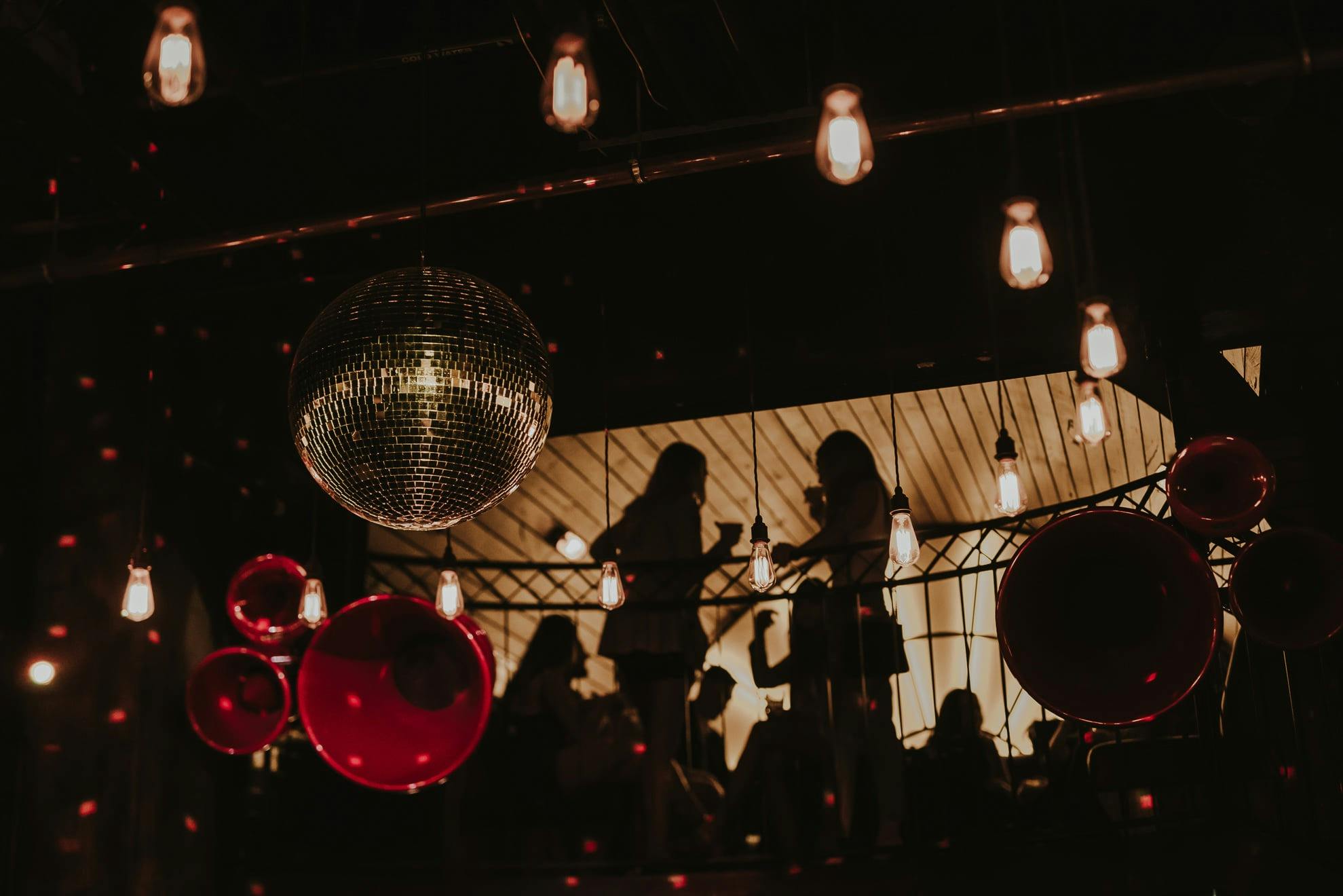 Red Void Speakers, with a silver disco ball hanging from above as two girls chat in the loft.