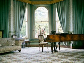 Grand Piano sitting in living room in front of large bay windows