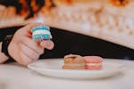 Table setting with a plate of colourful macaroons in pink, chocolate and blue with sprinkles.
