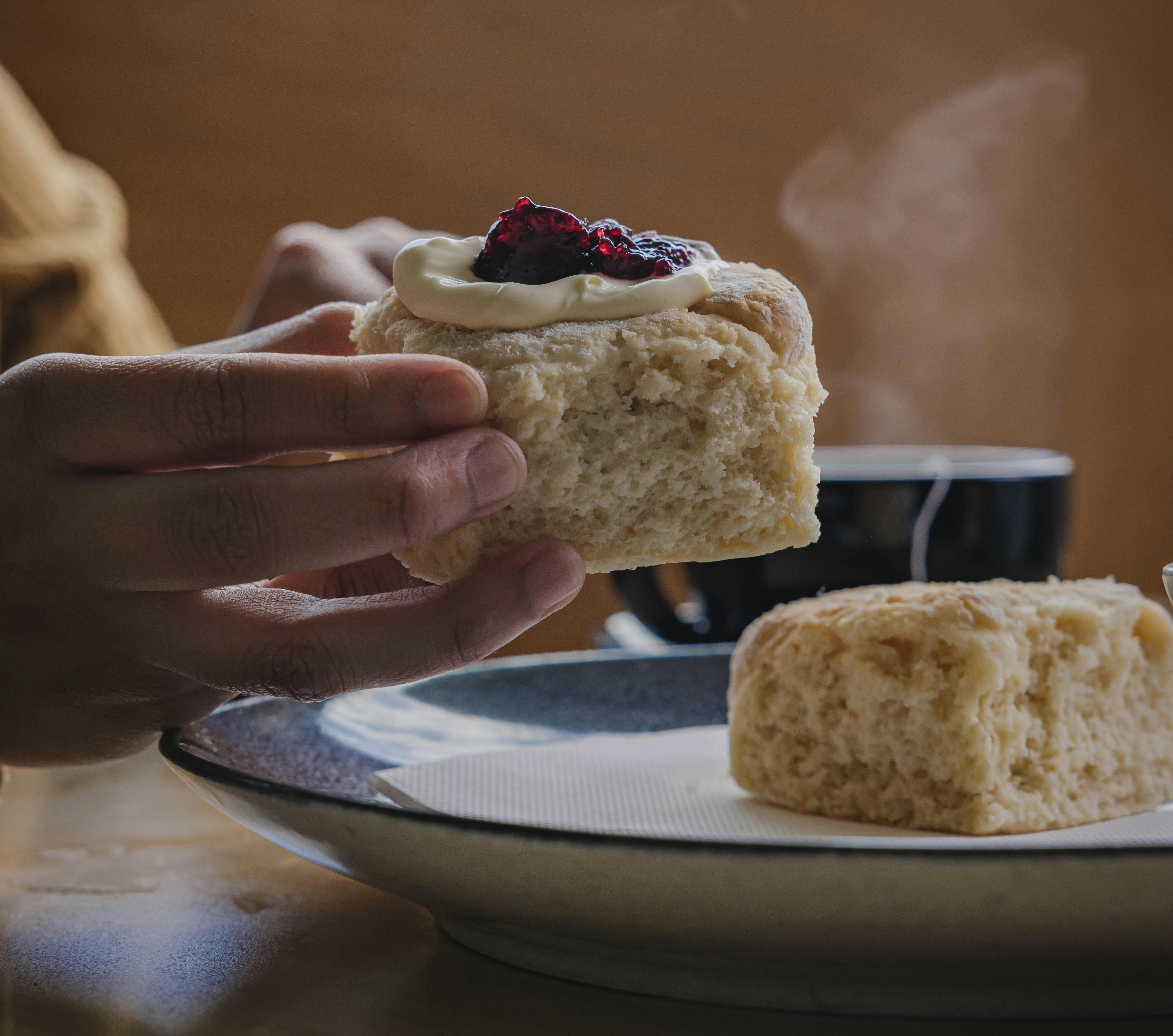 house baked scone with jam and cream, and a steaming cup of tea