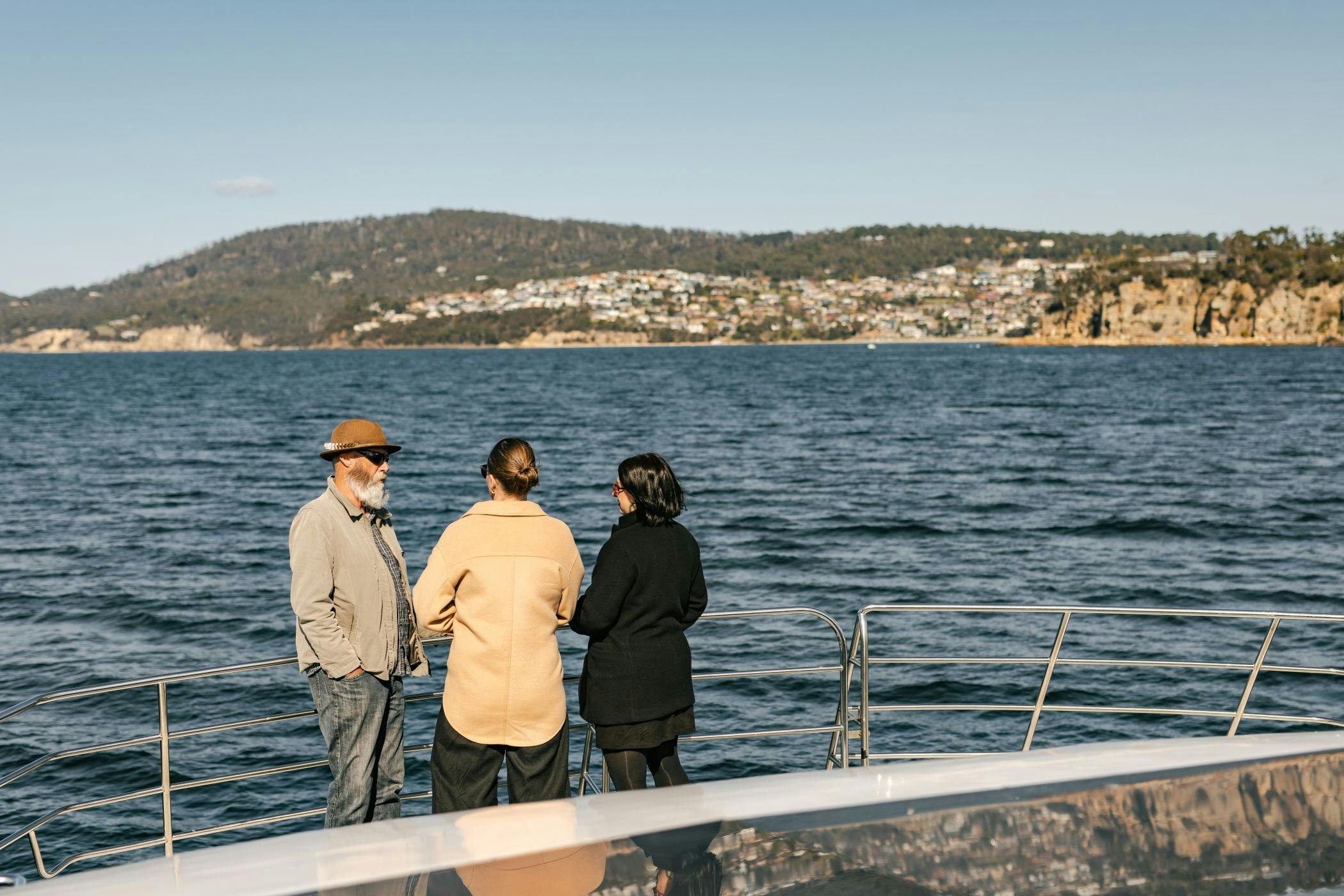 Three guests on the boat viewing deck looking at the view