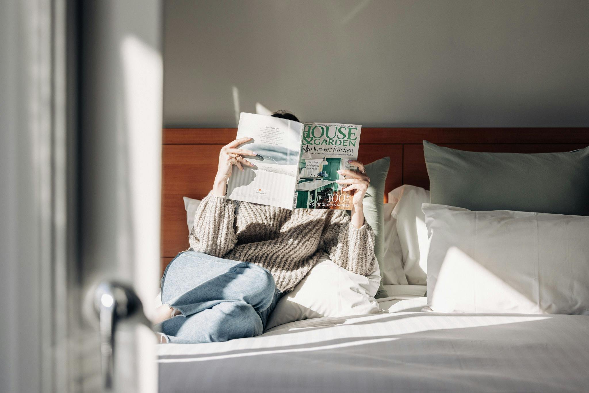 Lifestyle image of women on hotel bed reading magazine