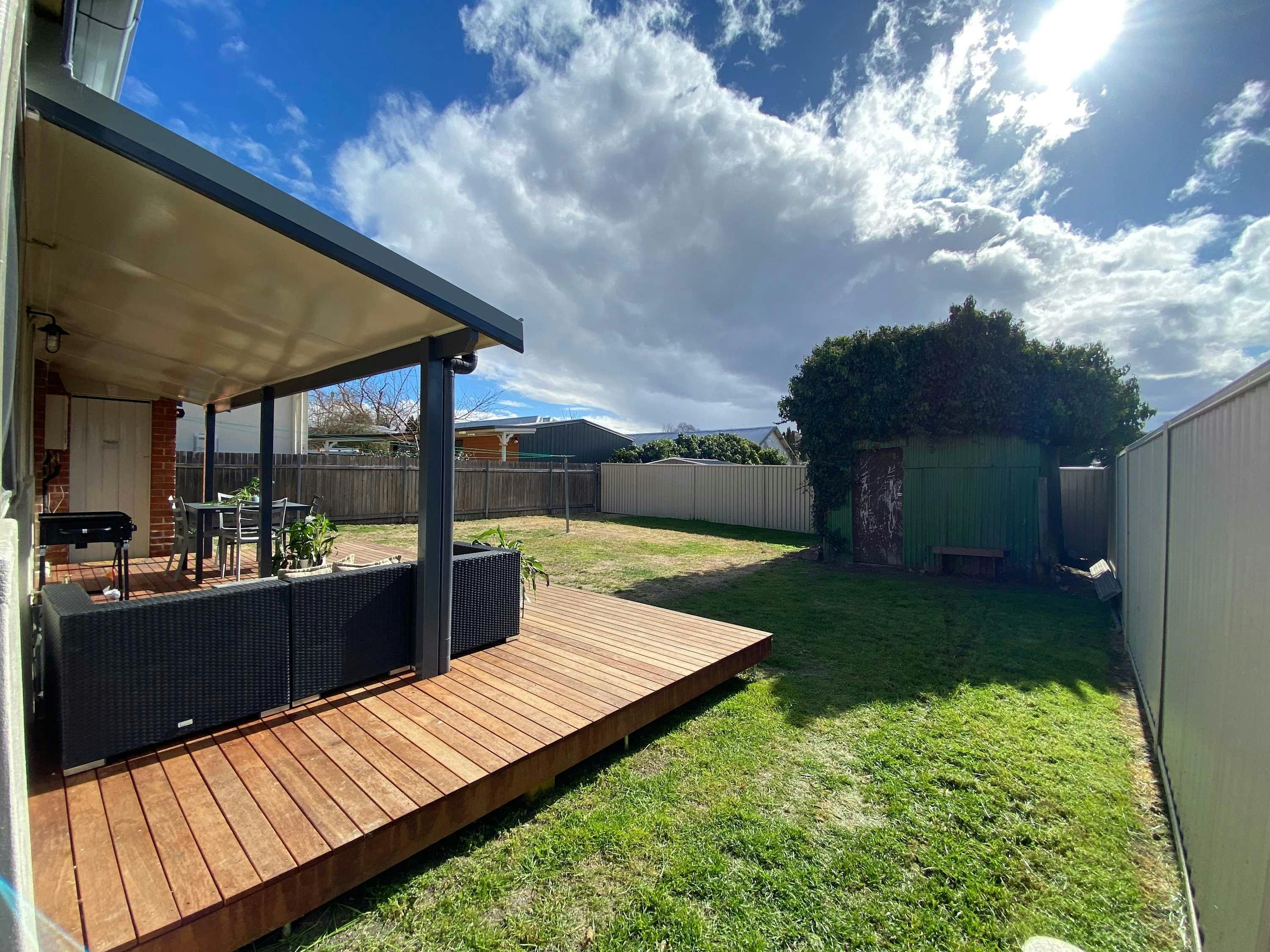 Large open grass are with large deck for outdoor dining