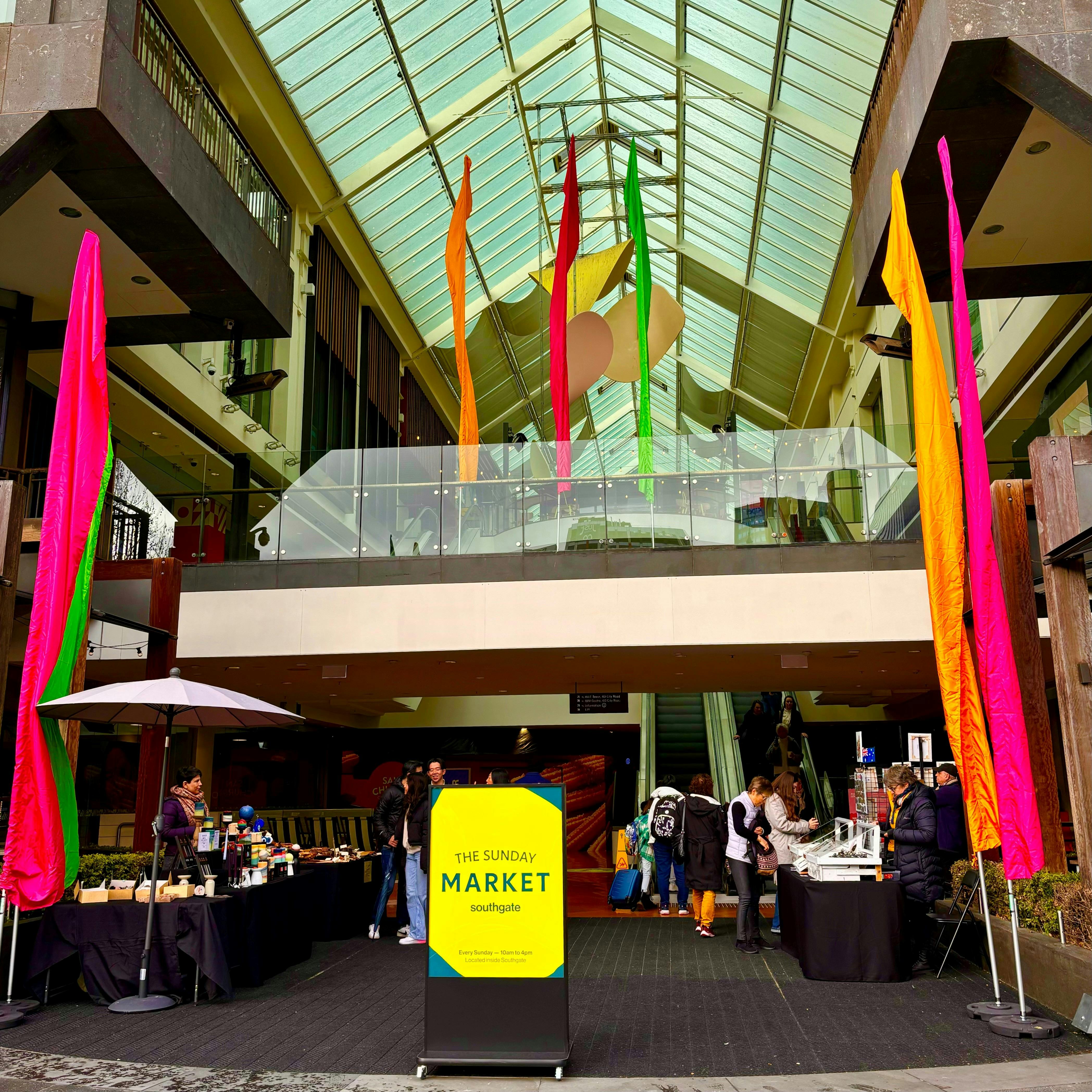Main entry to Southgate featuring market stall and bright, colourful flags