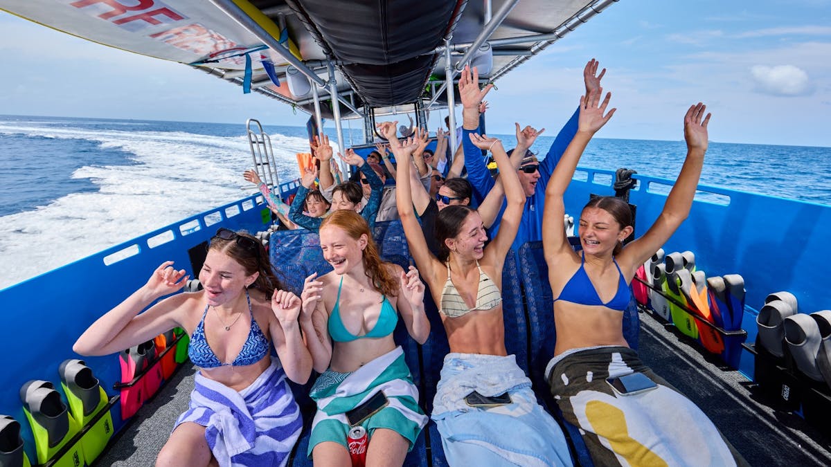 Guests experiencing a fast boat ride with hands in the air out of enjoyment