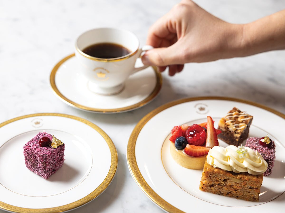 Overhead shot of a high tea with two plates of pastries and a cup of coffee.