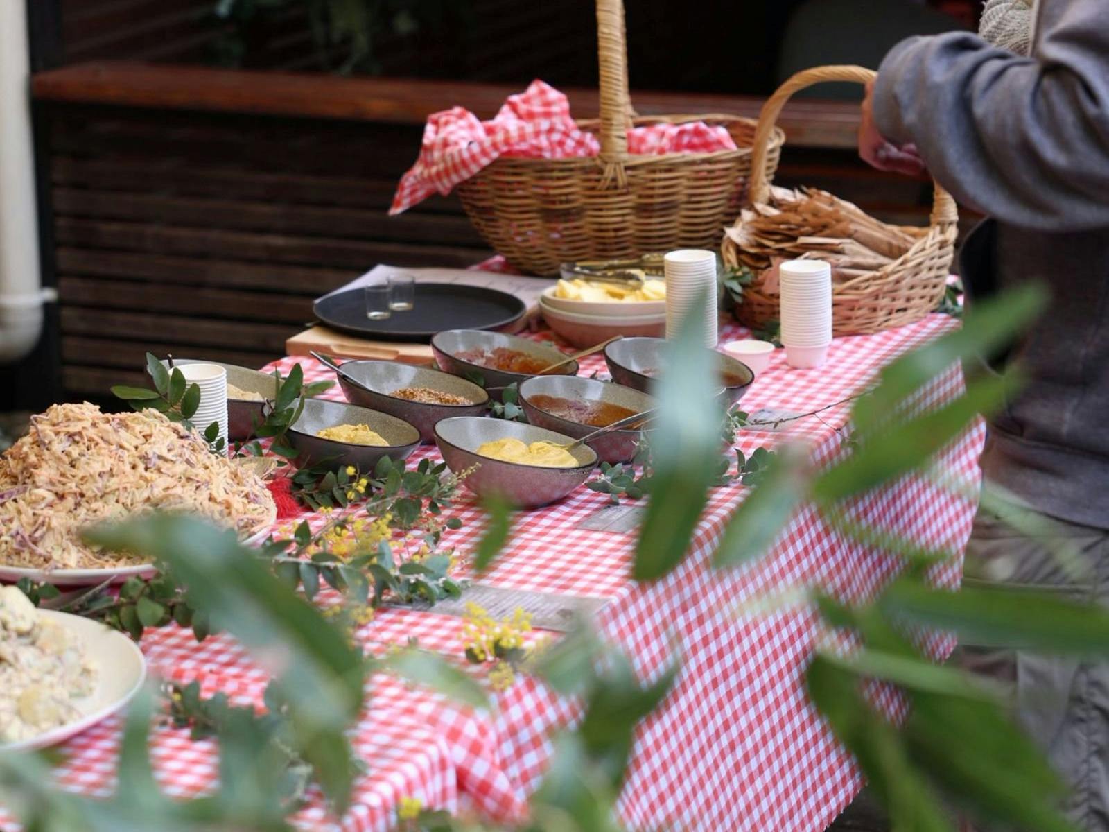 Table with red and white table cloth decorated with wattle and serving sauces and coleslaw